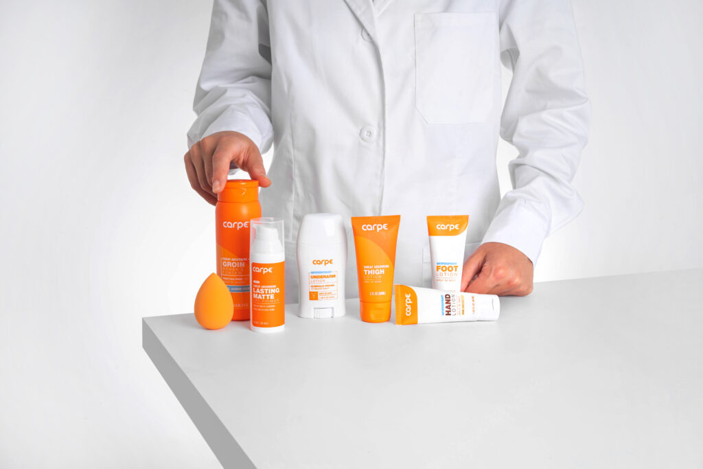 Image of a person in a lab coat standing at a table in front of Carpe products lined up